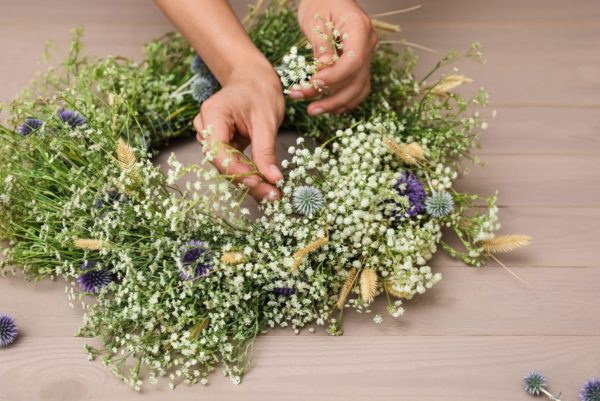 Woman,Making,Beautiful,Wreath,Of,Wildflowers,At,Wooden,Table,,Closeup